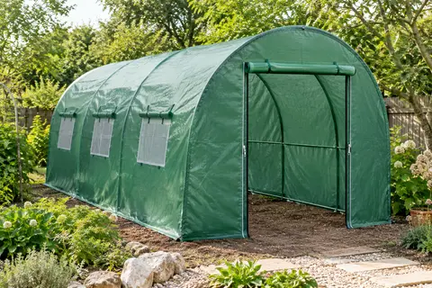 Housse verte renforcée sur un tunnel de jardin incurvé, avec porte zippée et ouvertures d’aération en maille.